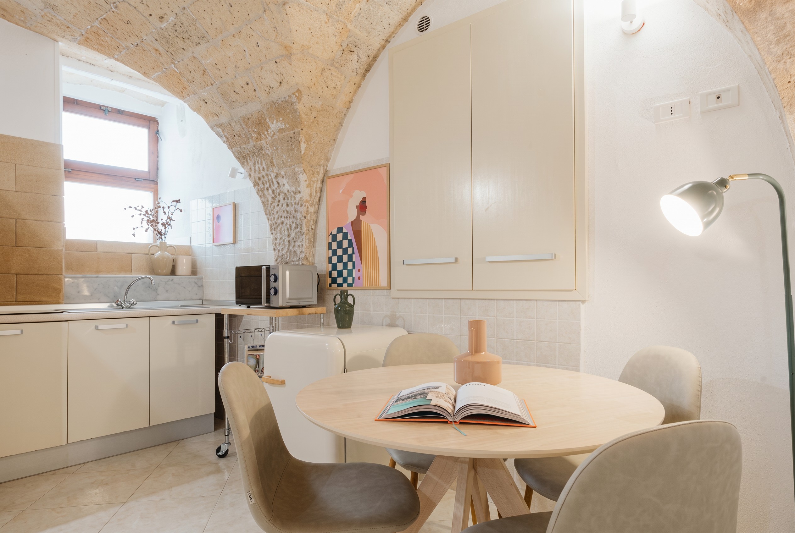 Dining table and kitchen beneath warm stone ceilings