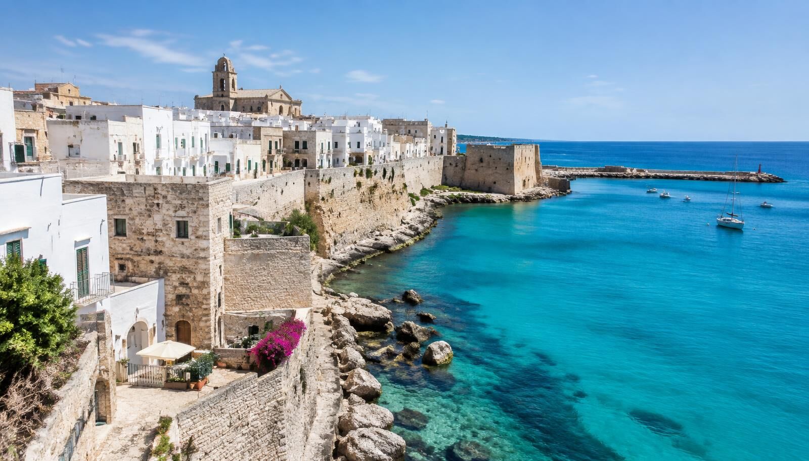 The iconic view of Otranto's white buildings overlooking the turquoise sea and the Aragonese castle walls.