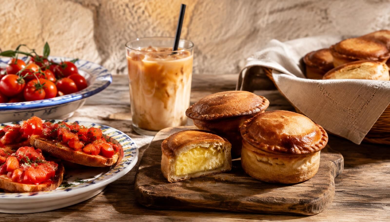 A close-up of a golden-brown Lecce pasticciotto pastry on a ceramic plate with a cup of coffee.